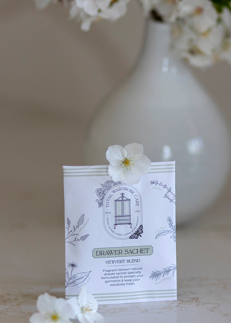Clothes moth deterrent drawer sachet with floral design, placed on a surface with flowers in the background.