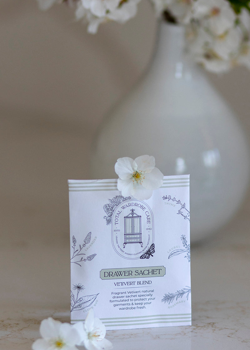 Clothes moth deterrent drawer sachet with floral design, placed on a surface with flowers in the background.