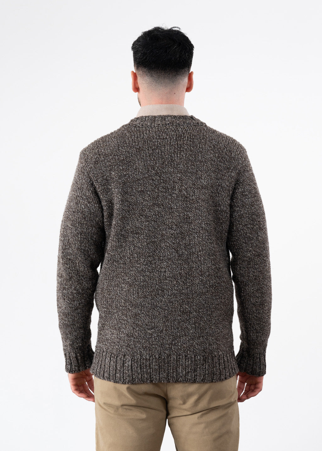 A man viewed from behind wearing a brown marl wool jumper over a beige shirt with khaki chino trousers.