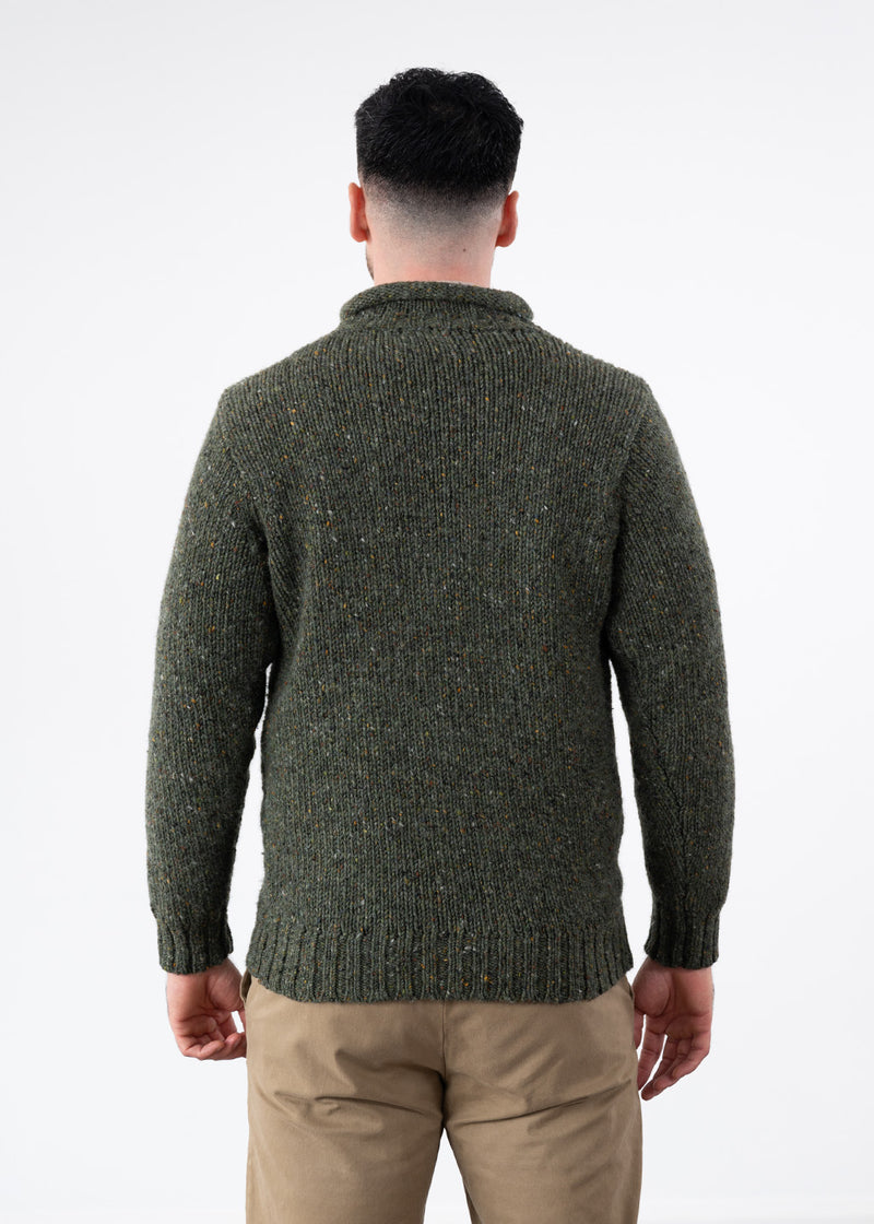 A man viewed from the back wearing a dark khaki green textured knit jumper and beige trousers, set against a plain white studio background.