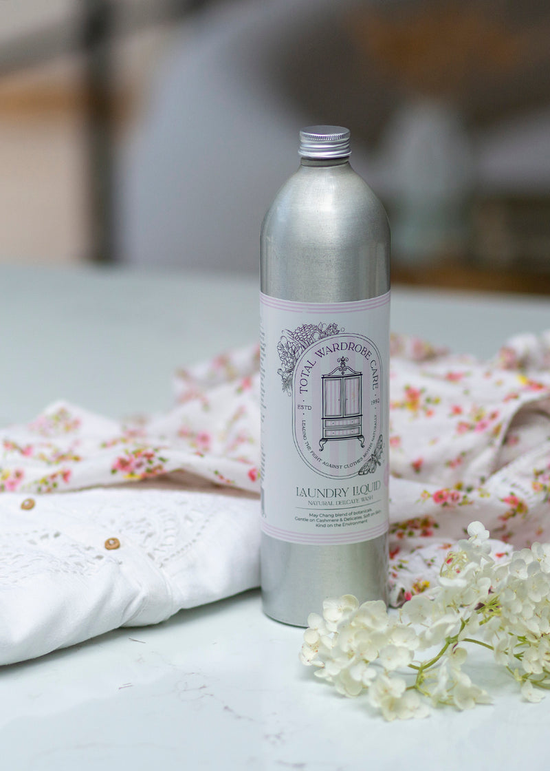 Silver bottle of delicate wool wash laundry detergent with flower and light clothing