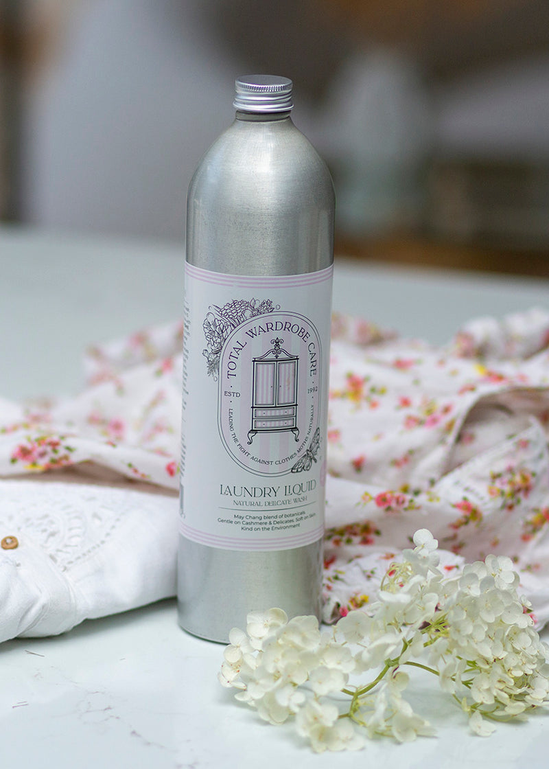 Silver bottle of delicate laundry detergent with flower and light clothing