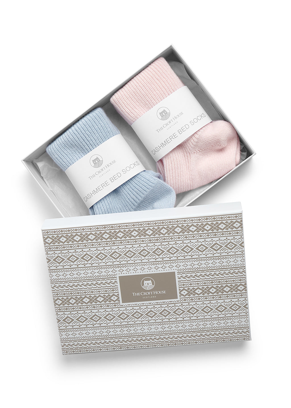 A gift set of two pairs of 100% cashmere socks in pastel blue and pink, presented in an open white box with a patterned lid. The socks are folded with white paper bands with the text 'THE CROFT HOUSE' and 'CASHMERE BED SOCKS'.