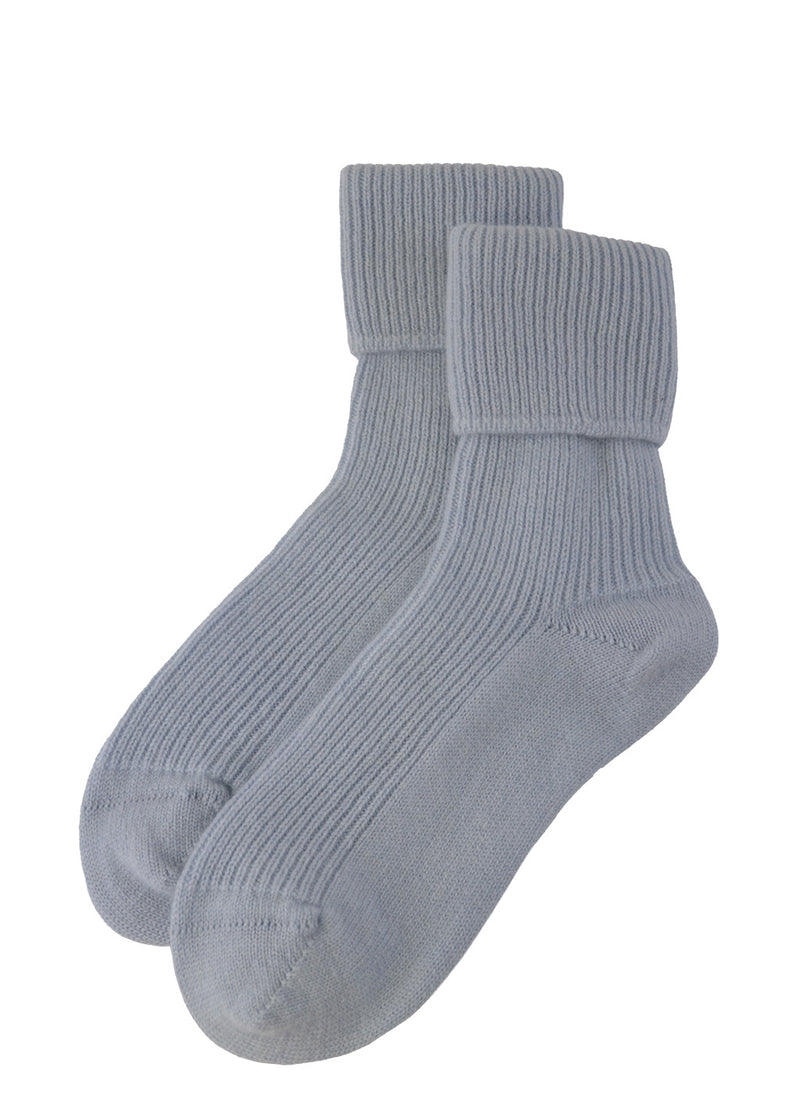 A pair of pale blue ribbed cashmere bed socks on a plain white background