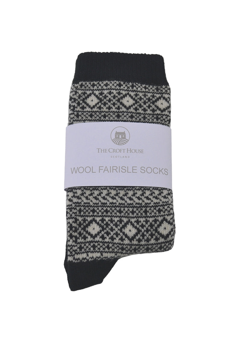 A pair of black and beige wool fair isle socks folded with a white packaging band on a white background